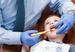 Orthodontist teaches child age 3-5 how to properly brush the teeth